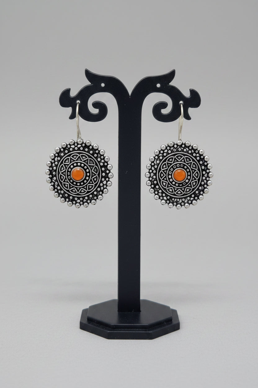 Premium oxidised mandala-inspired oxidized silver earrings with a central orange semi-precious stone.