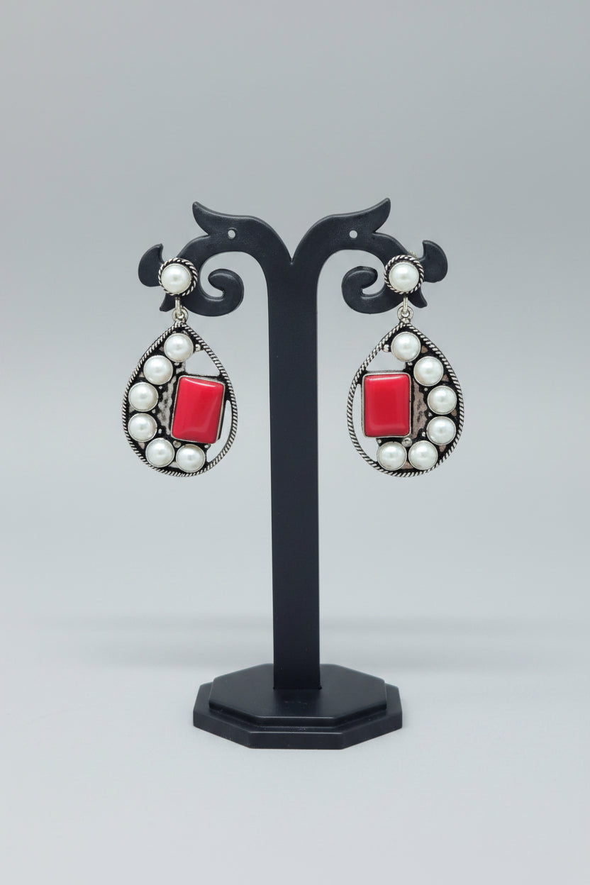 Premium handmade oxidised pearl-embellished teardrop earrings, with a vibrant red gemstone set amidst the pearls.