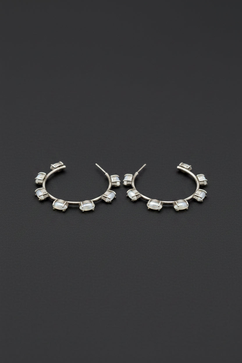 Pair of vintage oxidised silver hoop earrings with white stones on a dark gray background