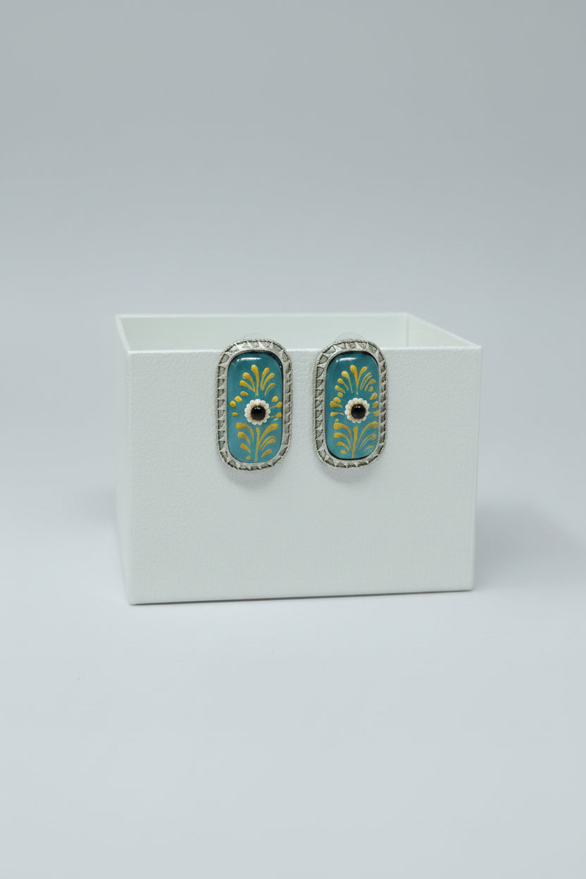 A pair of handcrafted rectangular oxidised stud earrings with meenakari on Turquoise Monalisa stone and gold floral motifs.