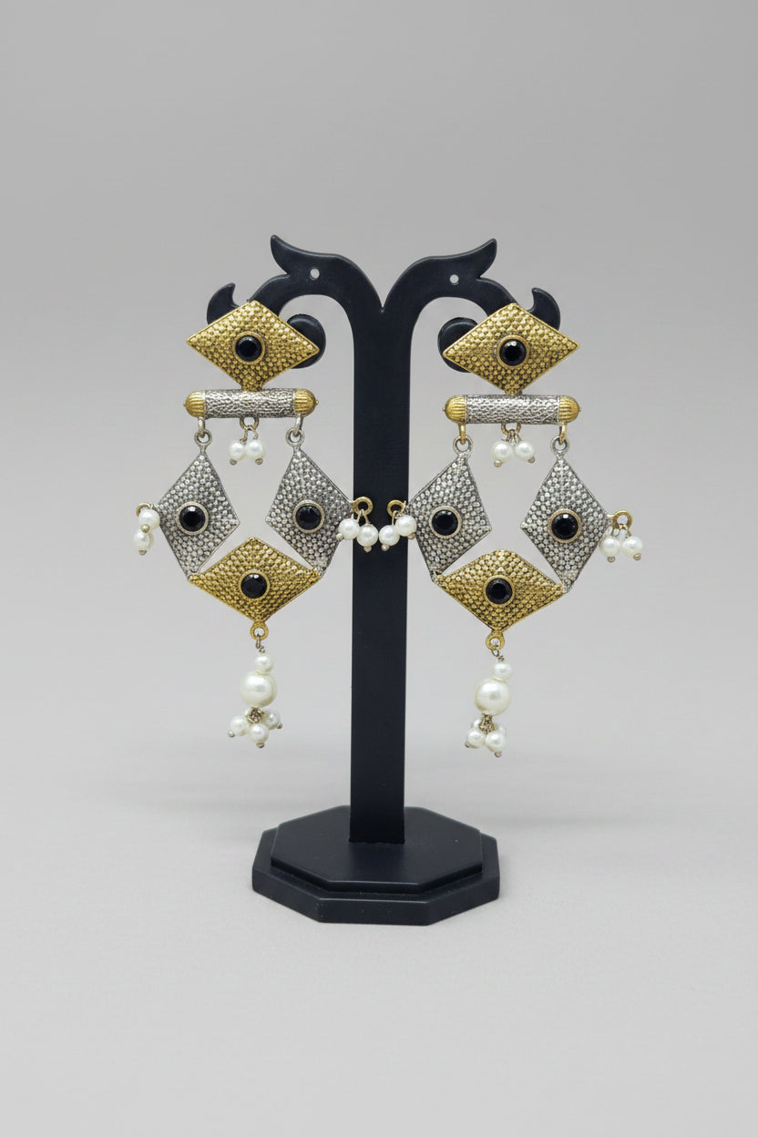 A pair of dual-tone geometric dangler earrings with black stone embellishments and pearl dangles.