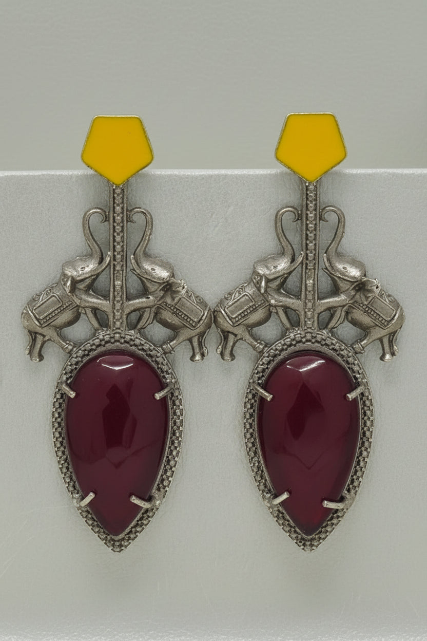Pair of  stylish indo-western oxidised dangler earrings with big red stone, yellow tops, and elephant motif.