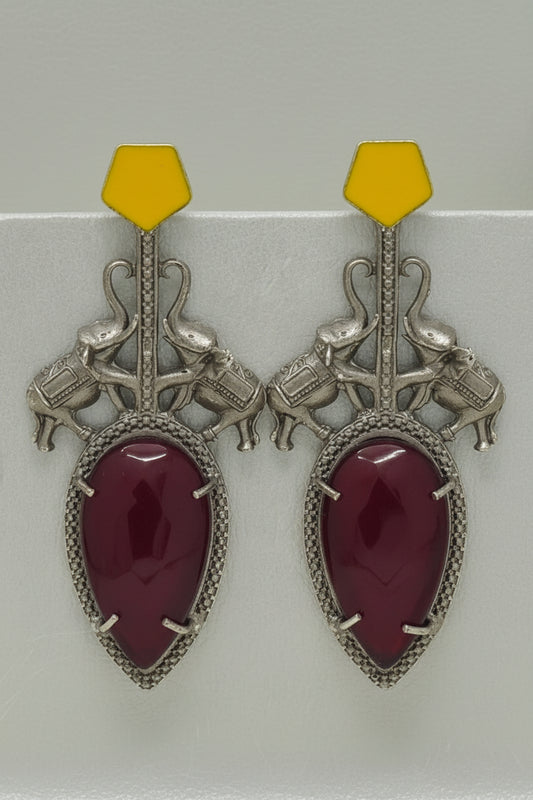 Pair of  stylish indo-western oxidised dangler earrings with big red stone, yellow tops, and elephant motif.