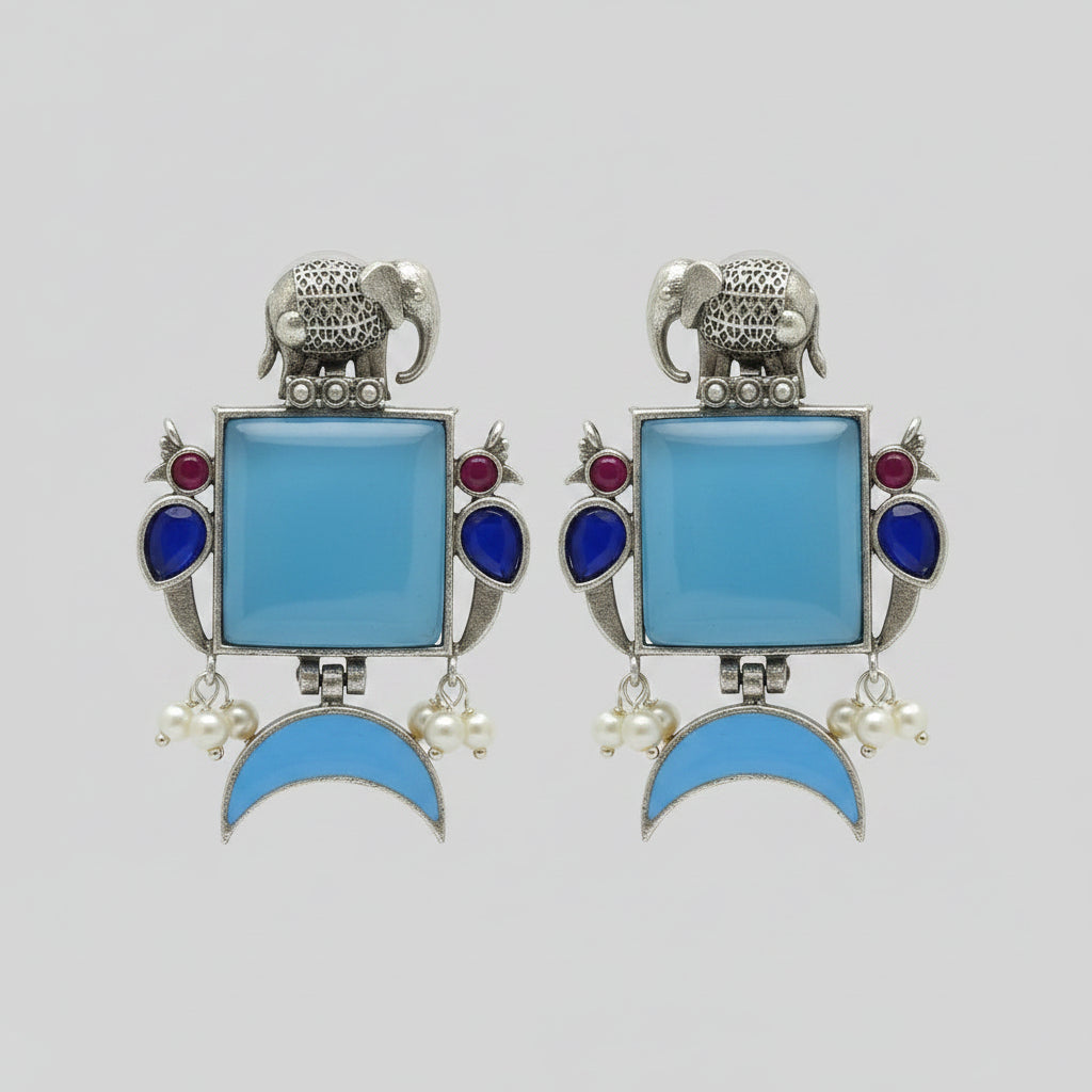 Pair of oxidised earrings with blue square stones, blue half moon stones, and silver elephant design.