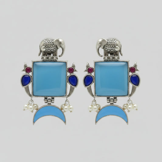 Pair of oxidised earrings with blue square stones, blue half moon stones, and silver elephant design.