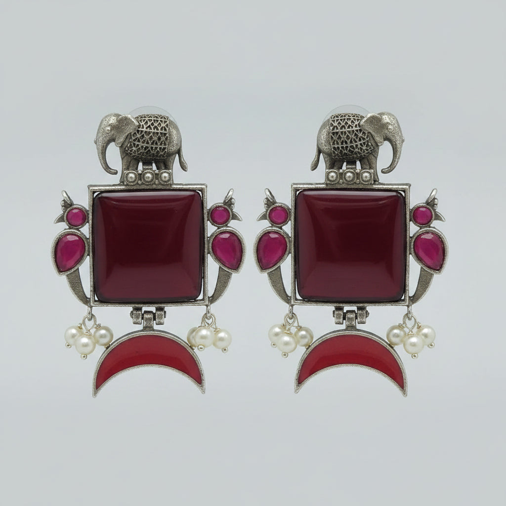 Pair of  oxidised earrings with red square stones,  red half moon stones, and silver elephant designs.