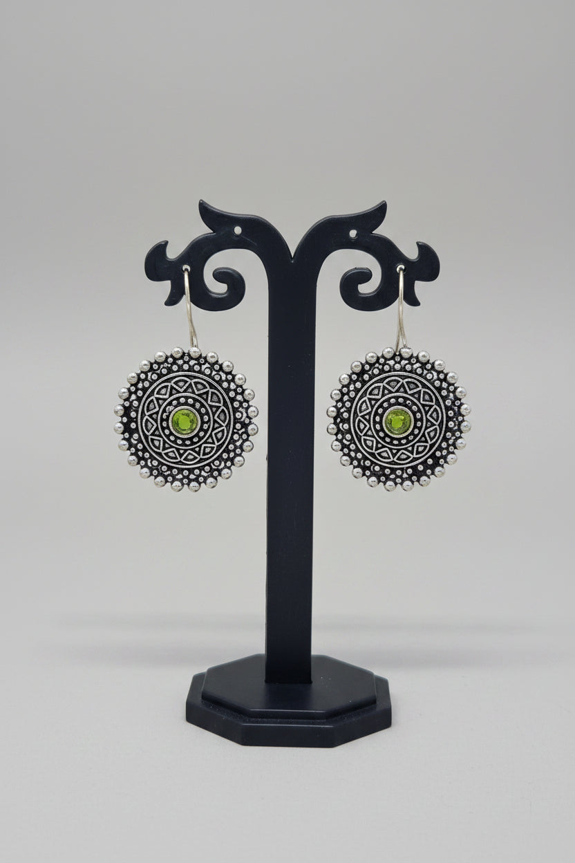 Premium oxidised mandala-inspired oxidized silver earrings with a central green semi-precious stone.