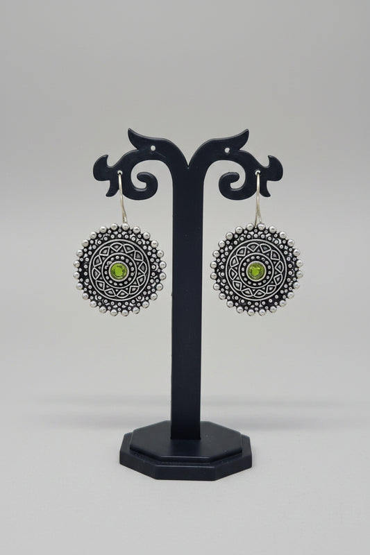 Premium oxidised mandala-inspired oxidized silver earrings with a central green semi-precious stone.