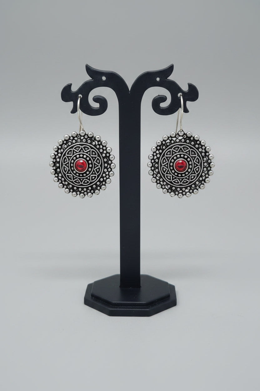 Premium oxidised mandala-inspired oxidized silver earrings with a central red semi-precious stone.