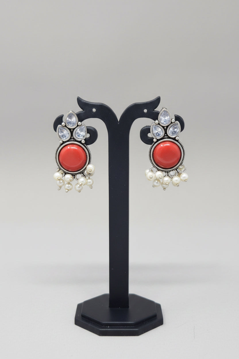 Premium oxidised Chandbali-style earrings with red onyx stones, surrounded by crystal accents, and pearl dangles.