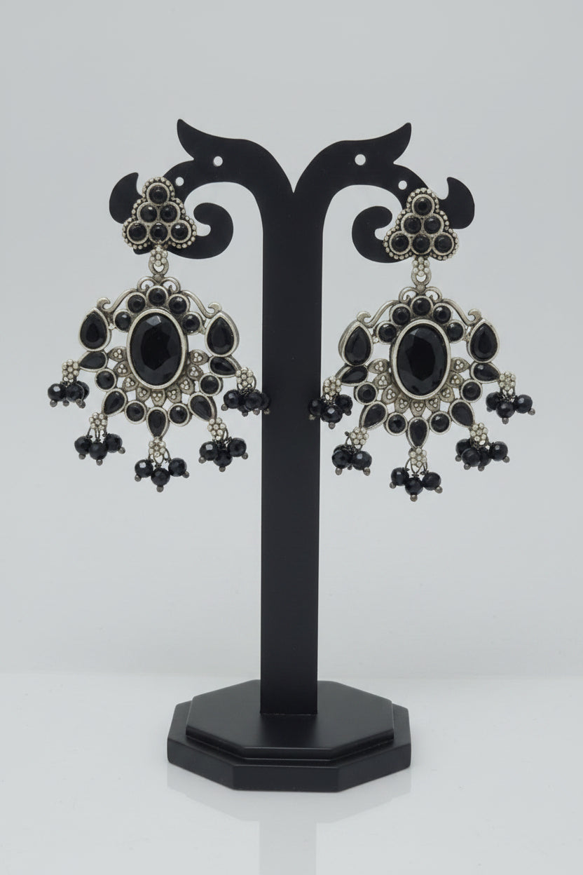 Antique oxidised silver dangler earrings with a floral motif and black Monalisa stonework, accompanied by black bead dangles and semi-precious stones .