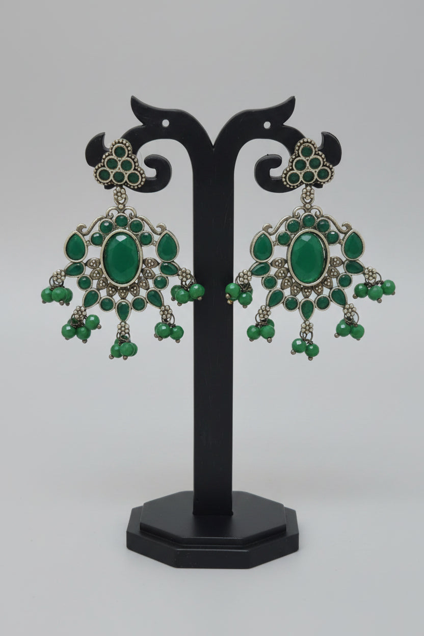 Antique oxidised silver dangler earrings with a floral motif and green Monalisa stonework, accompanied by green bead dangles and semi-precious stones .