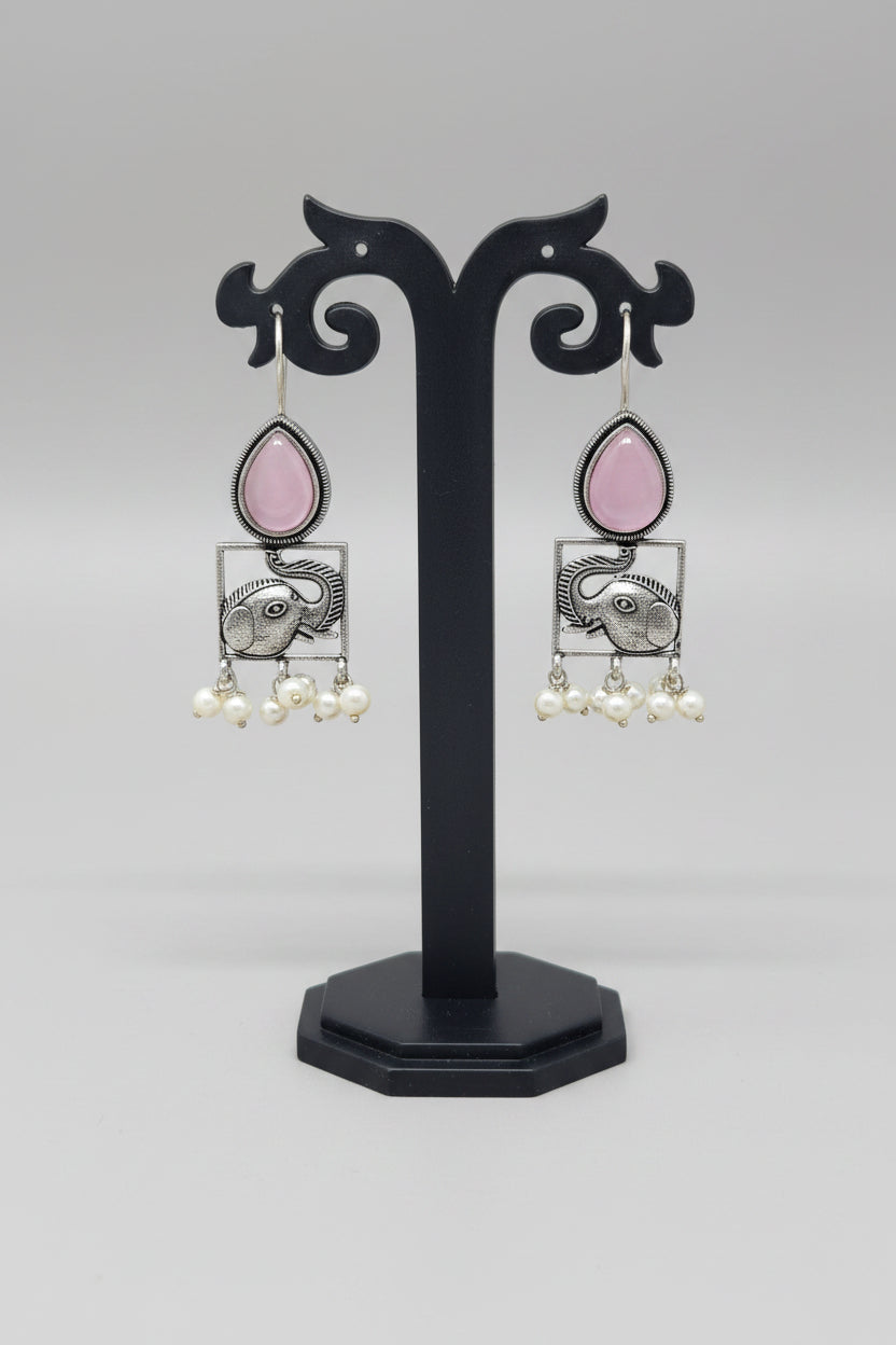 A pair of oxidised silver hook earrings featuring elephant motifs with teardrop-shaped pink semi-precious stones and pearl dangles.