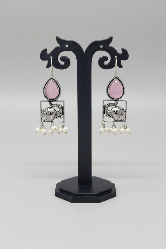 A pair of oxidised silver hook earrings featuring elephant motifs with teardrop-shaped pink semi-precious stones and pearl dangles.