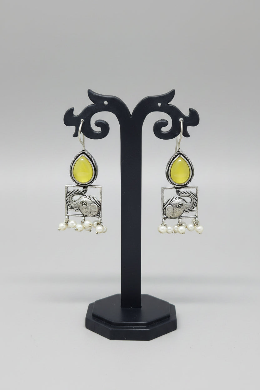 A pair of oxidised silver hook earrings featuring elephant motifs with teardrop-shaped yellow semi-precious stones and pearl dangles.