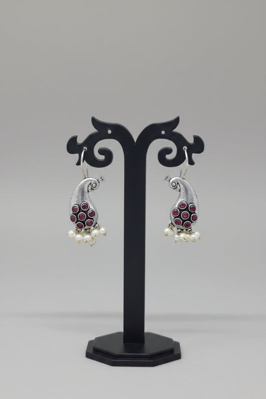 Premium oxidised antique silver peacock hook earrings with red colored stone accents and pearl drops.