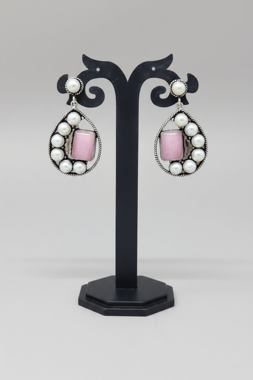 Premium handmade oxidised pearl-embellished teardrop earrings, with a vibrant pink gemstone set amidst the pearls.