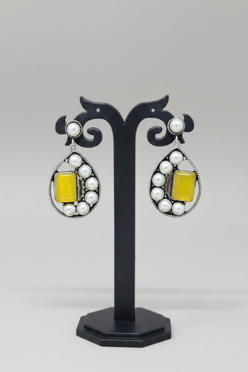 Premium handmade oxidised pearl-embellished teardrop earrings, with a vibrant yellow gemstone set amidst the pearls.