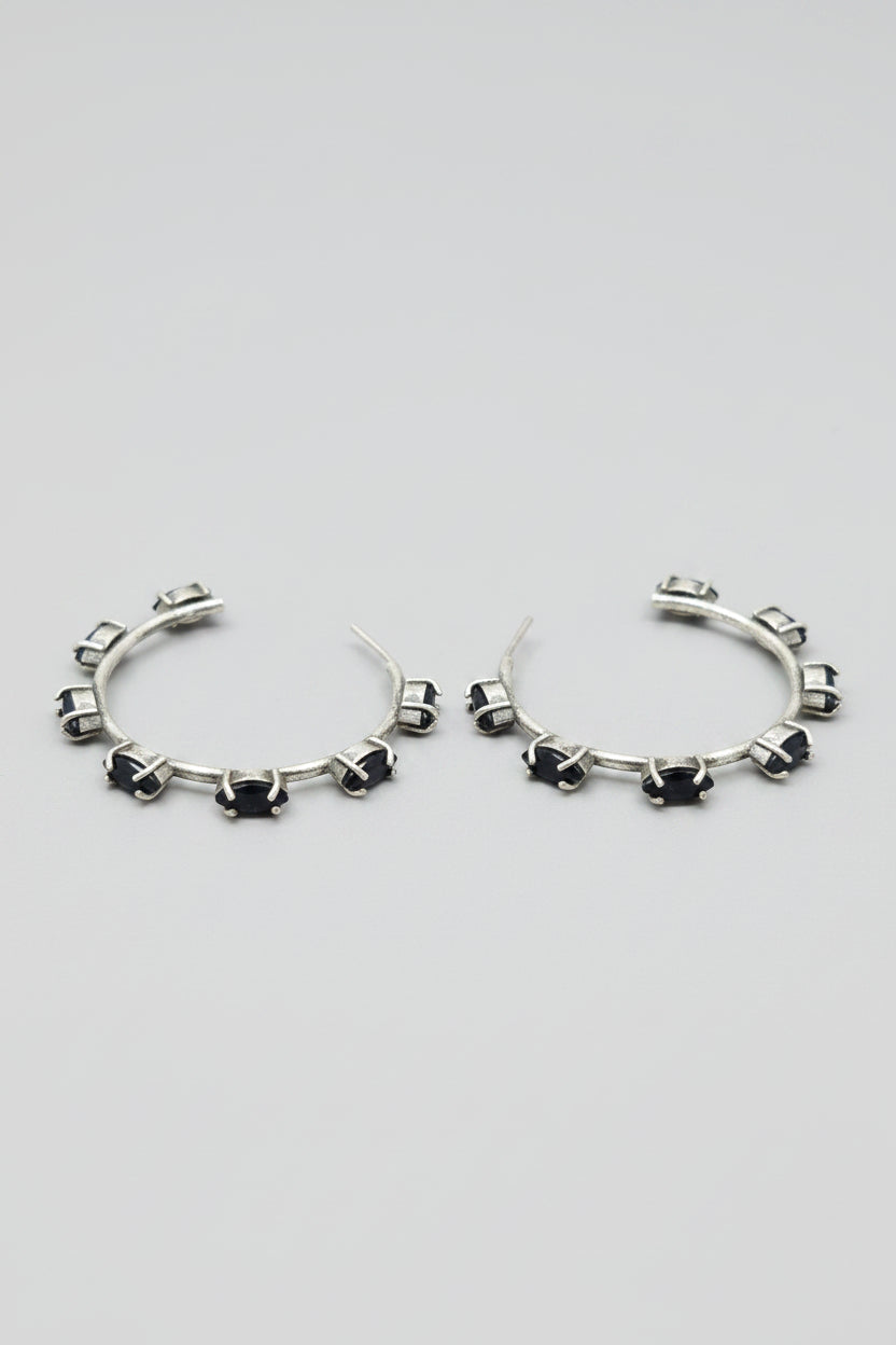 Pair of vintage oxidised silver hoop earrings with black stones on a light gray background