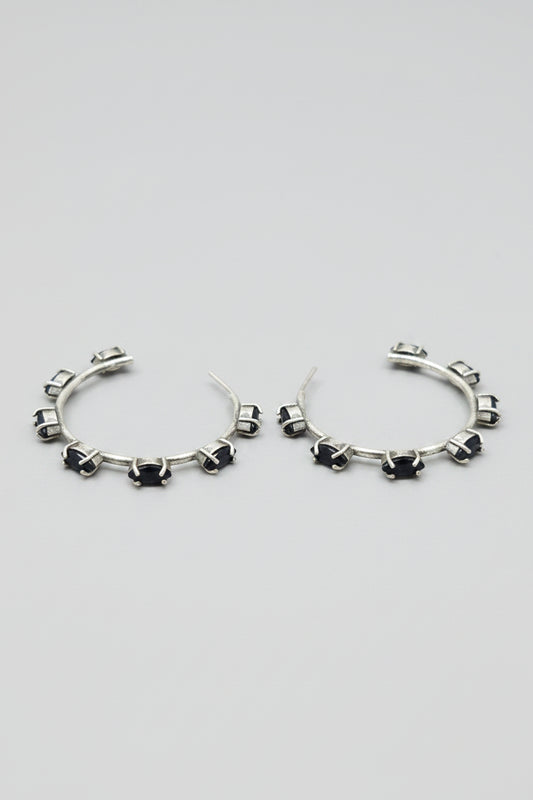 Pair of vintage oxidised silver hoop earrings with black stones on a light gray background
