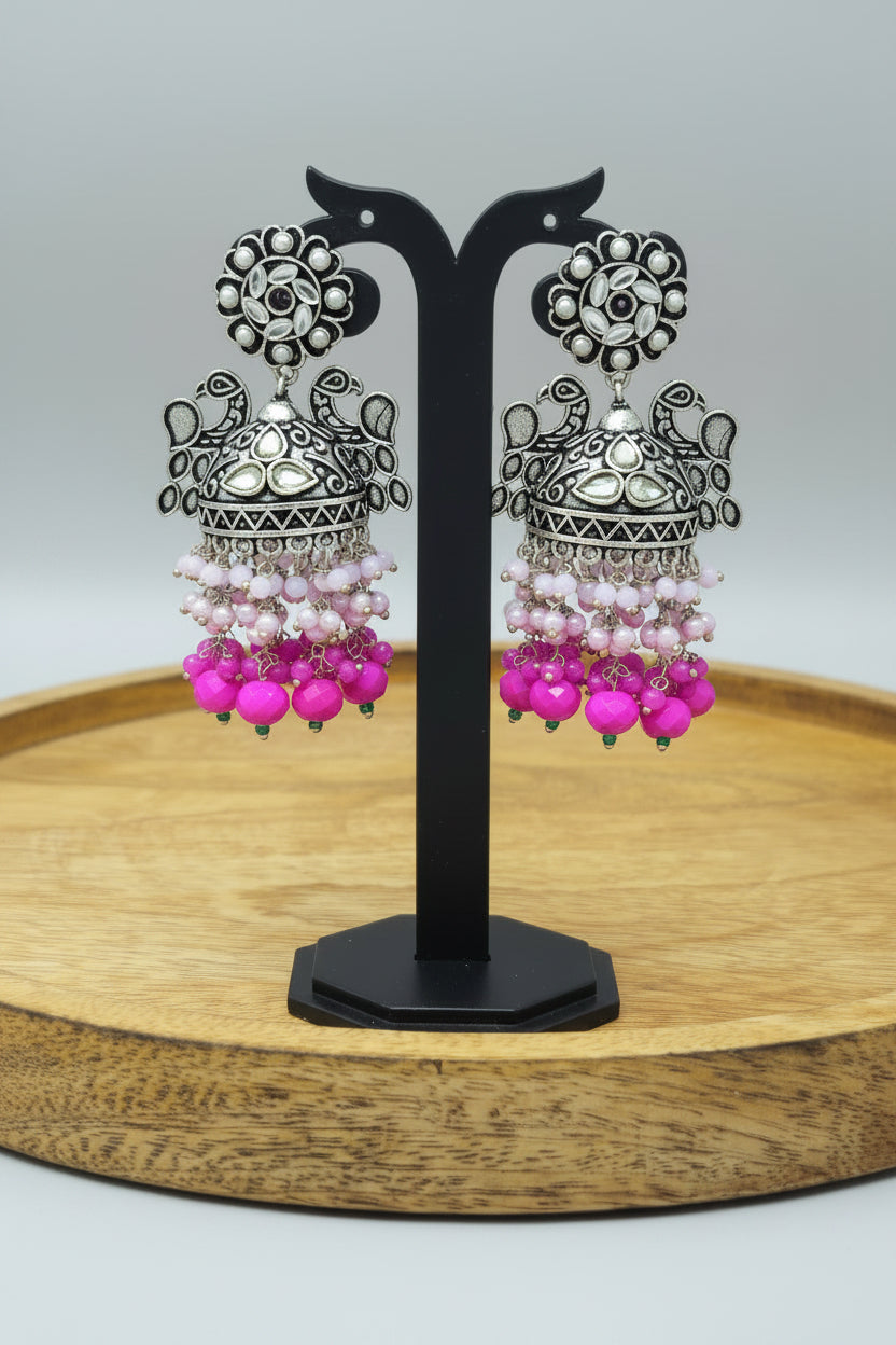 A pair of oxidized silver jhumka earrings with intricate Pachi Kundan work and hot pink color beaded 