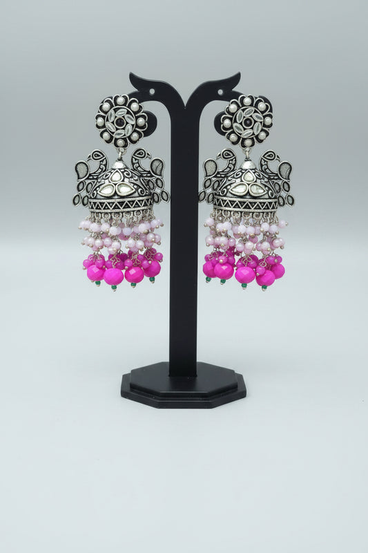 A pair of oxidized silver jhumka earrings with intricate Pachi Kundan work and hot pink color beaded 