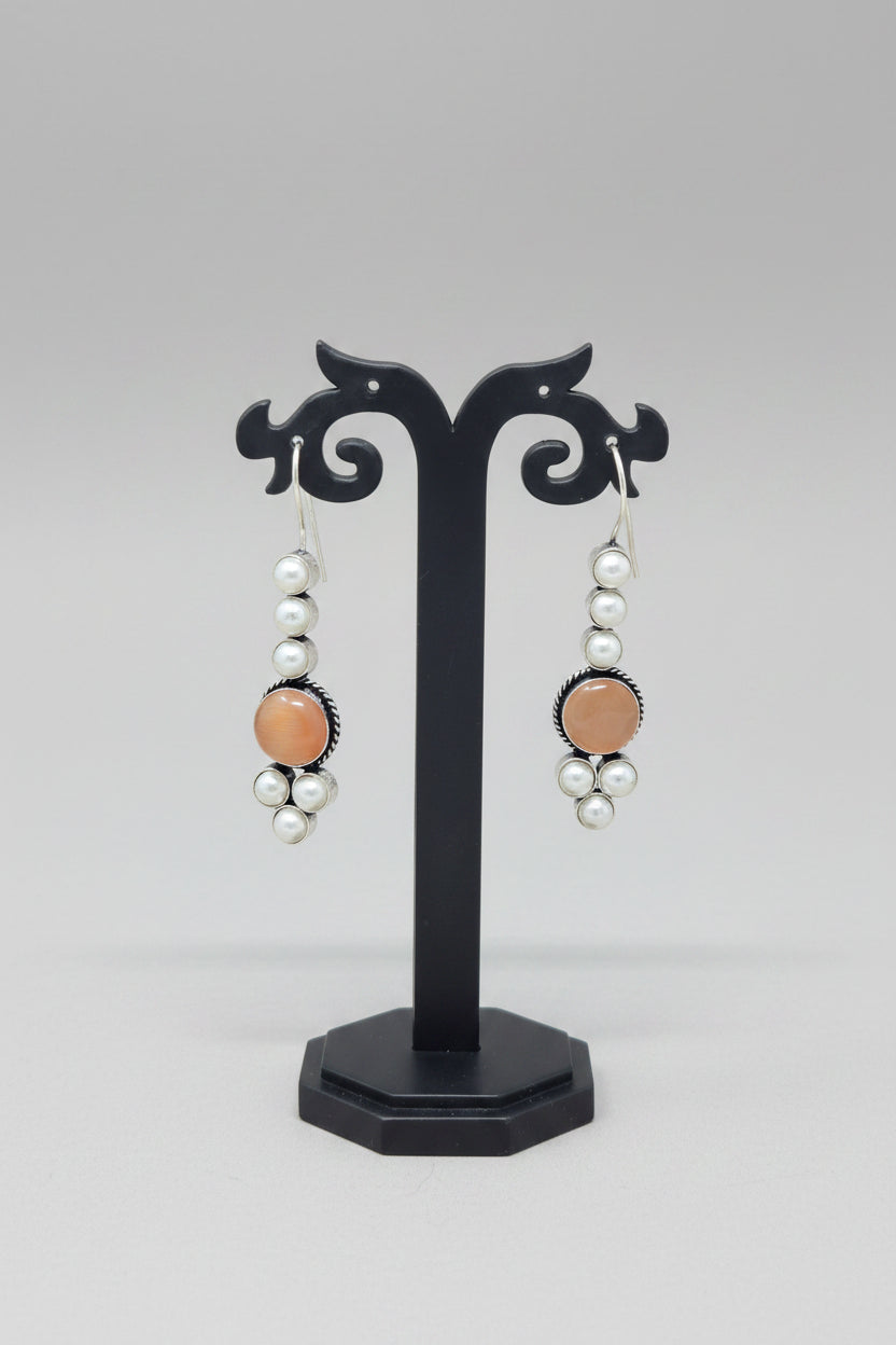 Pair of drop earrings with orange stones and pearls.