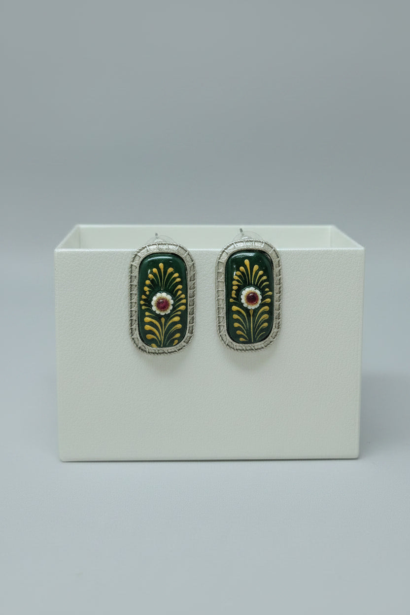 A pair of handcrafted rectangular oxidised stud earrings with meenakari on green Monalisa stone and gold floral motifs.