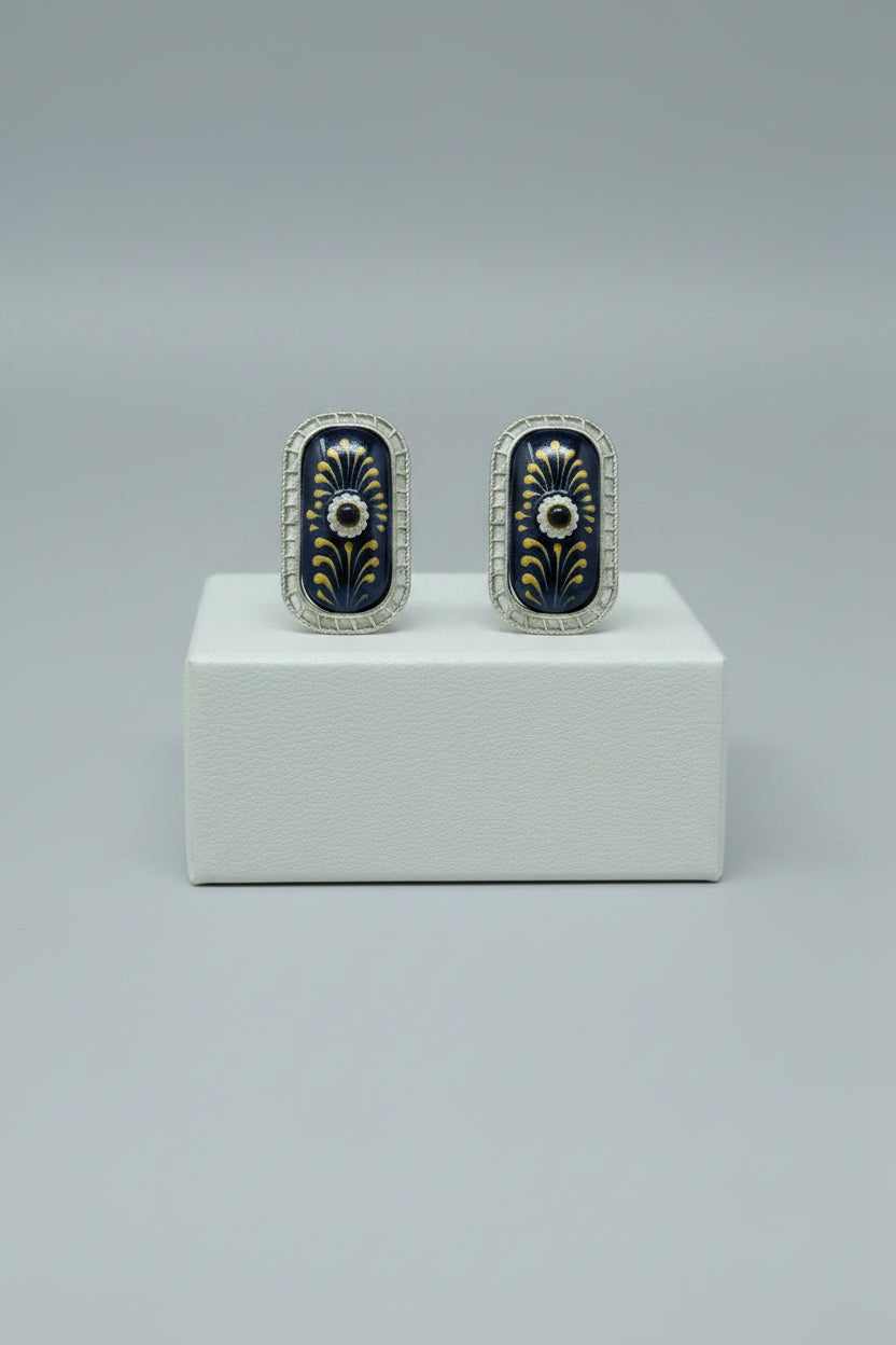 A pair of handcrafted rectangular oxidised stud earrings with meenakari on navy blue monalisa stone and gold floral motifs.