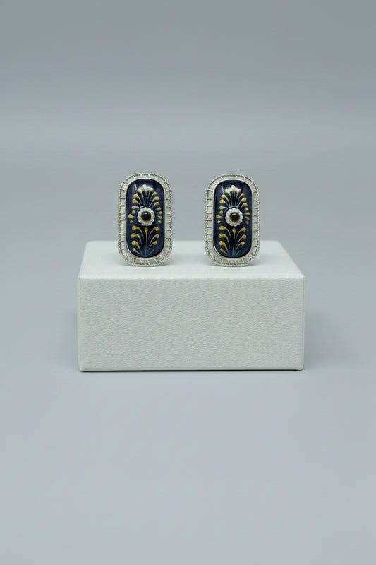 A pair of handcrafted rectangular oxidised stud earrings with meenakari on navy blue monalisa stone and gold floral motifs.