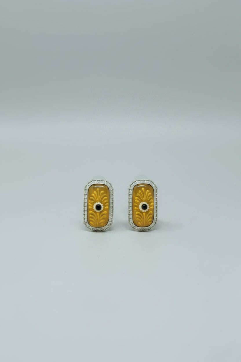 A pair of handcrafted rectangular oxidised stud earrings with meenakari on yellow Monalisa stone and gold floral motifs.