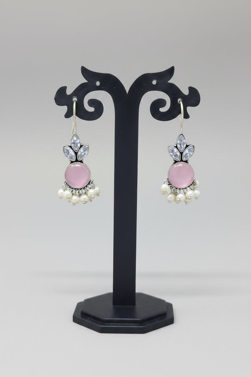  Oxidized silver hook earrings with a floral motif, pearl dangles. The earrings are adorned with a large pink semi-precious stone and smaller crystal-like stones.