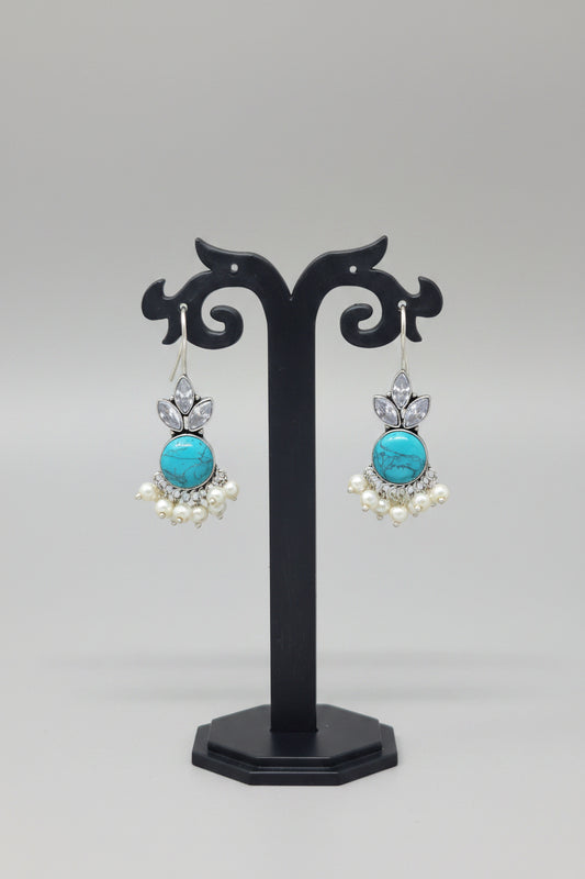  Oxidized silver hook earrings with a floral motif, pearl dangles. The earrings are adorned with a large turquoise semi-precious stone and smaller crystal-like stones.