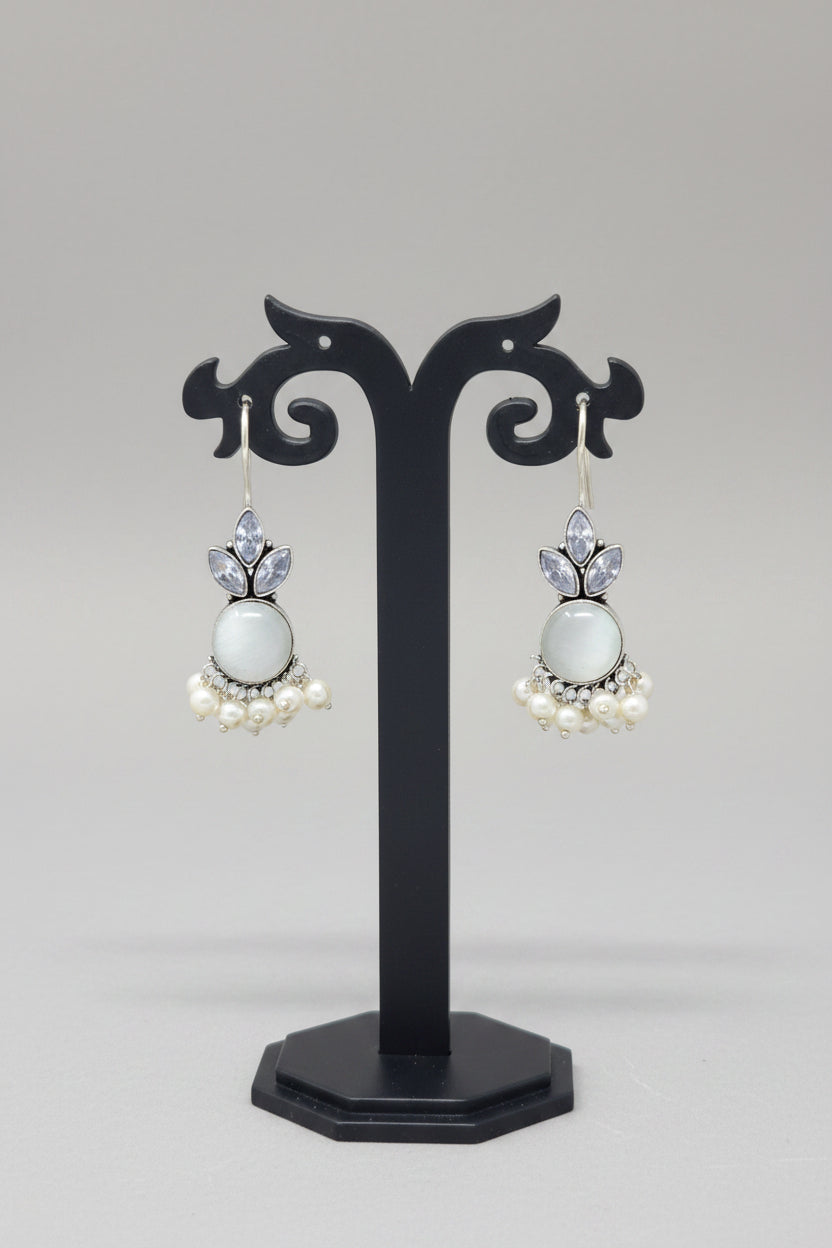  Oxidized silver hook earrings with a floral motif, pearl dangles. The earrings are adorned with a large white semi-precious stone and smaller crystal-like stones.