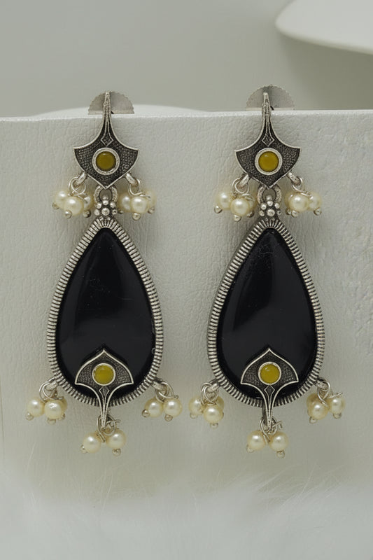 Pair of oxidised black teardrop earrings with pearl-like beads on a white background