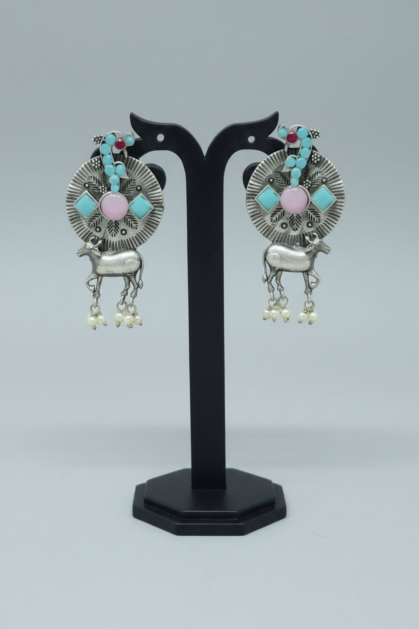 A pair of oxidized silver earrings with a tribal-inspired Nandi design, featuring mint pastel-colored semi-precious stones and dangling pearls.